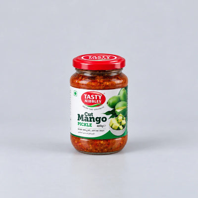 A glass jar of Tasty Nibbles Cut Mango Pickle with a red lid and white label, set against a light gray background.
