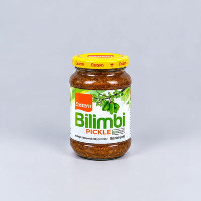 A glass jar of Eastern Bilimbi Pickle with a yellow lid and a white label featuring green and orange branding, set against a plain light gray background.
