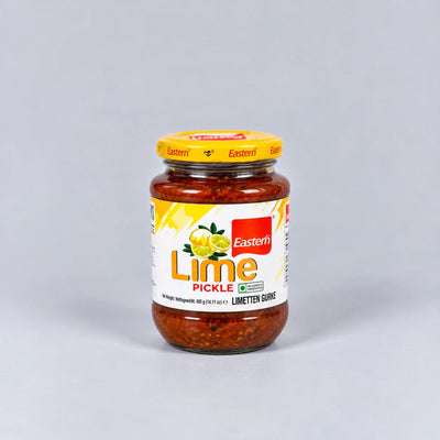 A glass jar of Eastern Lime Pickle with a yellow lid and a white label featuring yellow and red graphics, set against a plain light gray background.
