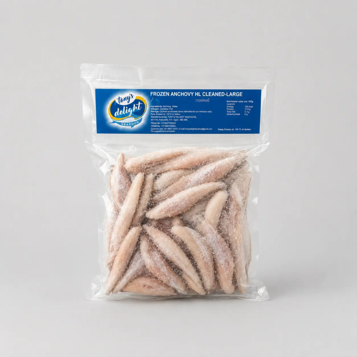 A clear plastic bag of frozen anchovies, labeled 'Kool Delight Frozen Anchovy Ml Cleaned Large', containing several pale pinkish-beige frozen anchovies, set against a neutral light gray background.