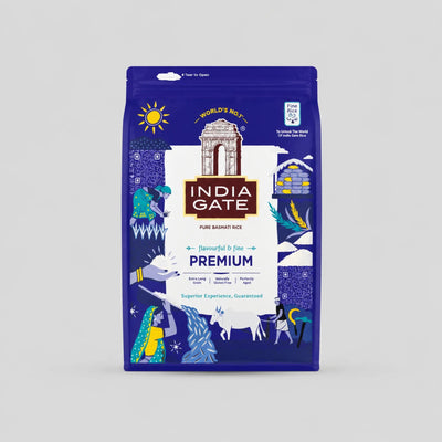 A bag of India Gate Premium Pure Basmati Rice on a light gray background. The packaging is primarily deep blue with white and gold illustrations and text, featuring the India Gate archway logo and decorative elements of a horse, peacock, and traditional motifs.