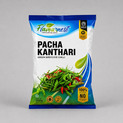 A 100g bag of Flavournest Pacha Kanthari (Green Bird's Eye Chilli) on a neutral gray background. The packaging is primarily white with blue and green accents, featuring a graphic of fresh green chilies with red peppers, and a yellow 'Made in India' badge.