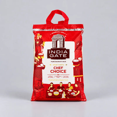 A red bag of India Gate Chef Choice Pure Bashati Rice standing upright on a light gray studio background. The packaging features a white central label with the India Gate brand name and illustrations of people dining and kitchen scenes.