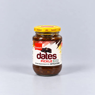 A glass jar of Eastern Dates Pickle, Datteln Gure, featuring a yellow lid and a white label with red and black text, set against a plain light gray background.