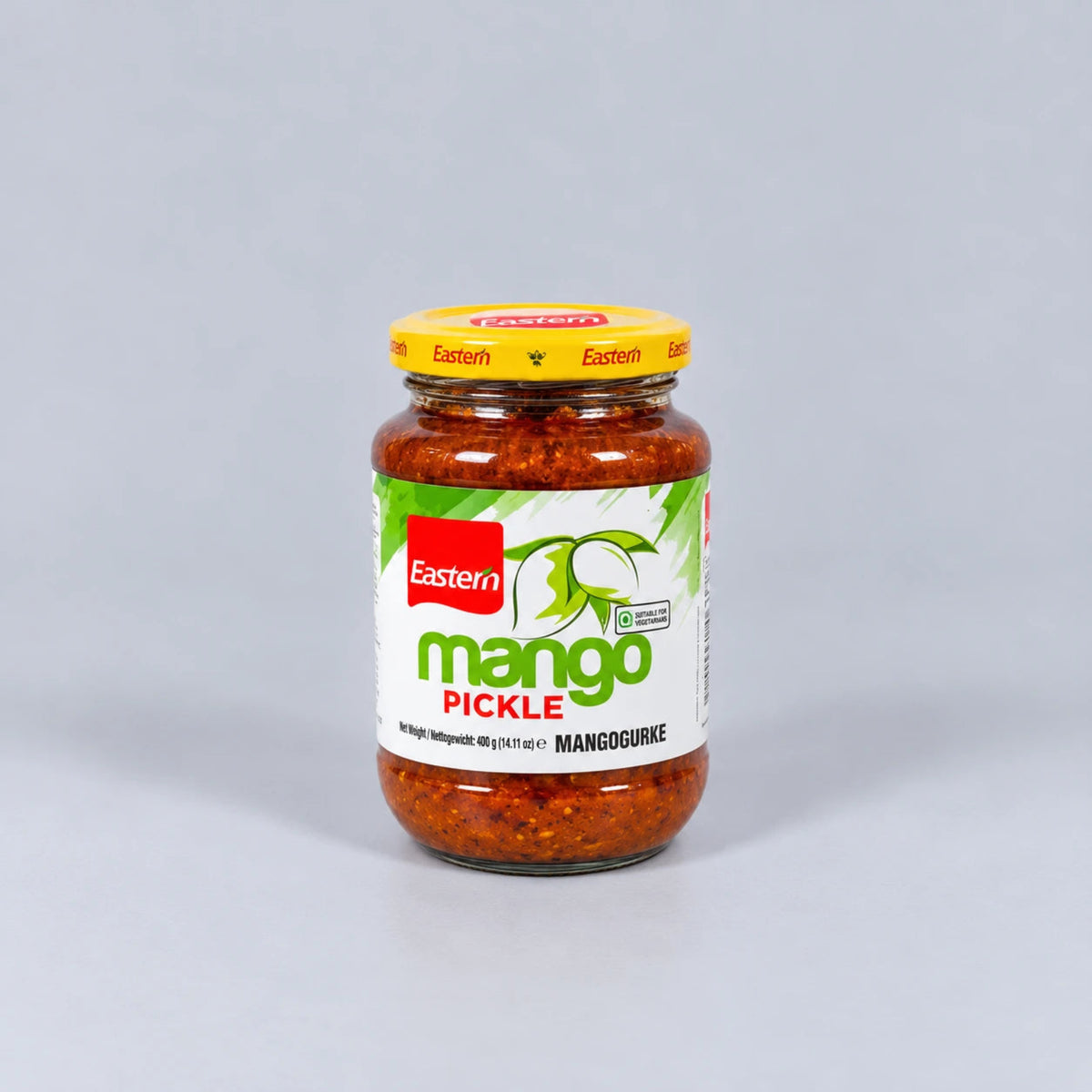 A glass jar of Eastern Mango Pickle with a yellow lid and a white, green, and red label, set against a plain light gray background.
