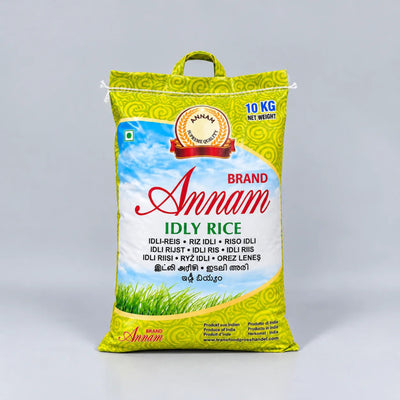 A 10 kg bag of Annam Brand Idly Rice, featuring a bright yellow-green bag with a blue sky and green grass illustration, set against a neutral gray background.