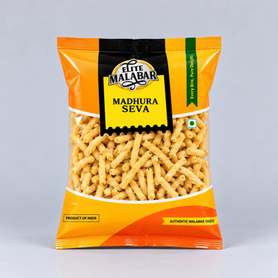 A bag of Elite Malabar Madhura Seva snacks, featuring a bright orange and yellow packaging with a clear window showing the golden-brown cylindrical sev pieces inside, set against a neutral gray background.
