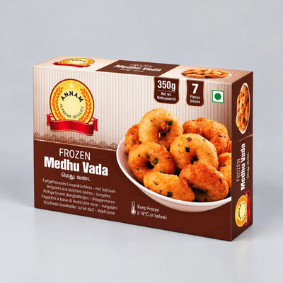 A box of Annam Frozen Medhu Vada, featuring a brown and beige design with a photo of golden-brown fried fritters on a white plate. The packaging includes the Annam brand logo and product details.