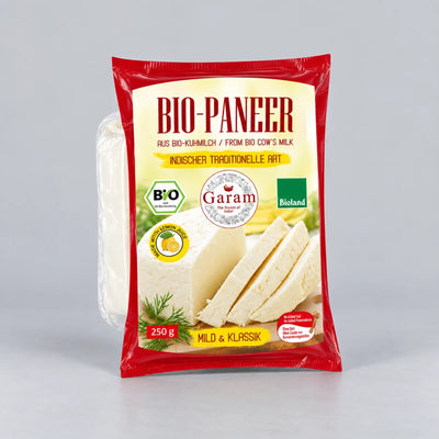 A package of Bio-Paneer Garam traditional German cheese, 250g, in a red and cream-colored bag with a photo of sliced cheese on the front, set against a neutral gray background.