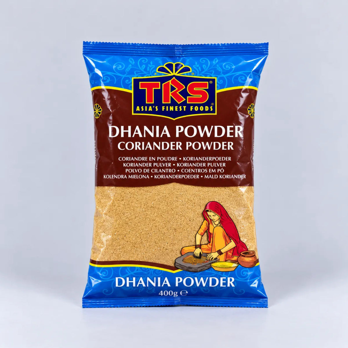 A 400g bag of TRS Dhania Powder (Coriander Powder) on a light gray background. The packaging is blue and brown with a clear window showing the golden-brown powder inside, and features the TRS logo and an illustration of a woman grinding coriander.