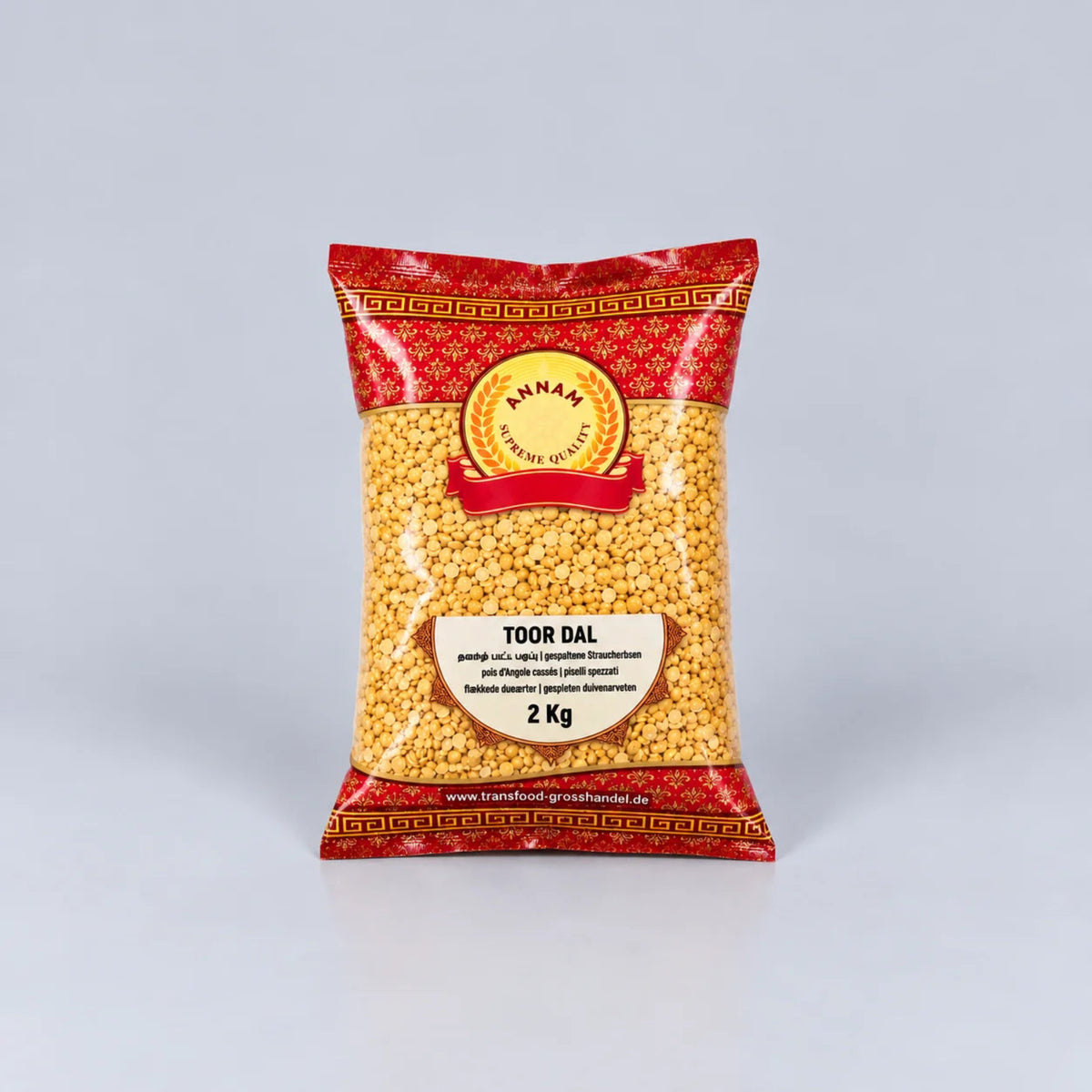 A 2 kg bag of Annam Premium Quality Tour Dal (mung bean) in a red and gold patterned package with a clear window showing the yellow-beige mung beans inside, set against a light gray background.
